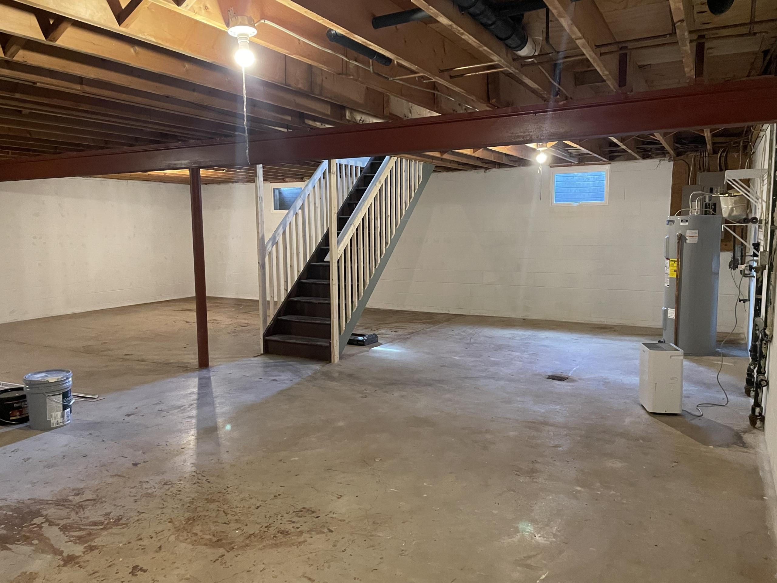 Unfinished basement with stairs and water heater