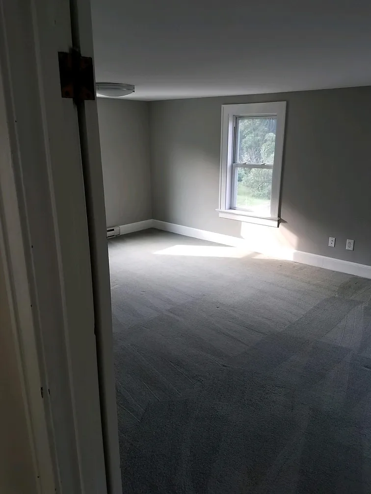 Empty bedroom with gray carpet and window