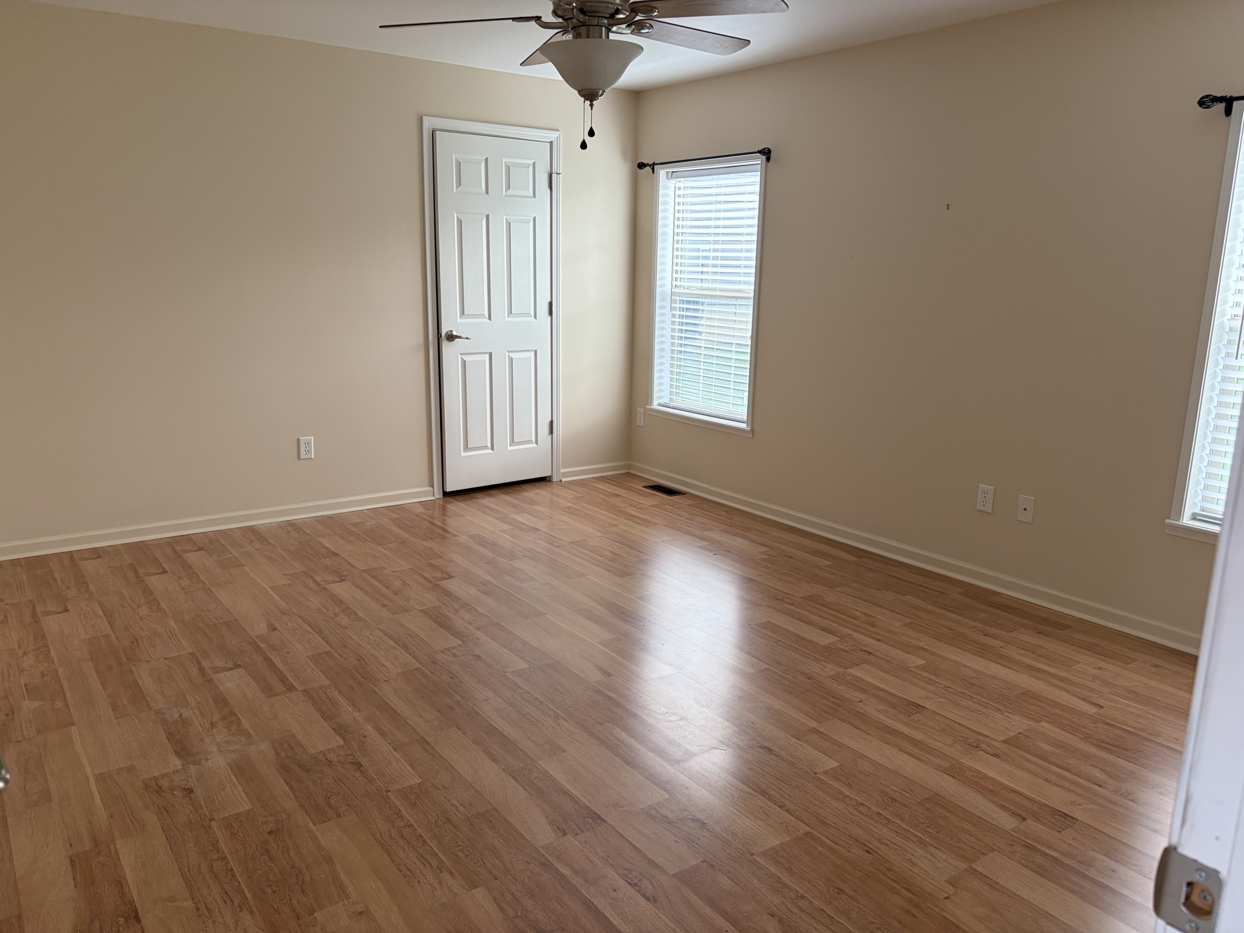 Empty bedroom with wood floor and white door
