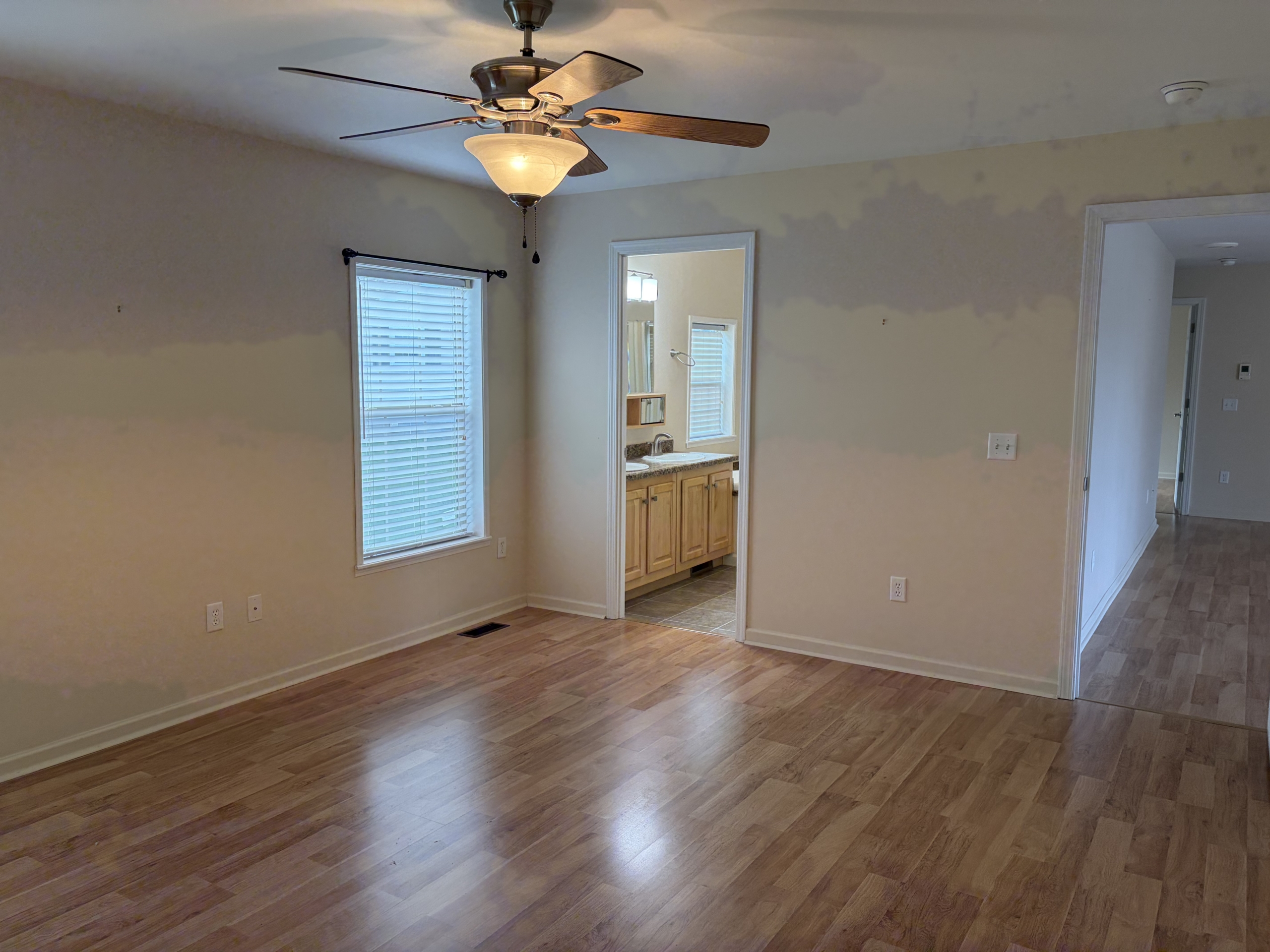 Spacious bedroom with wood floors and ceiling fan