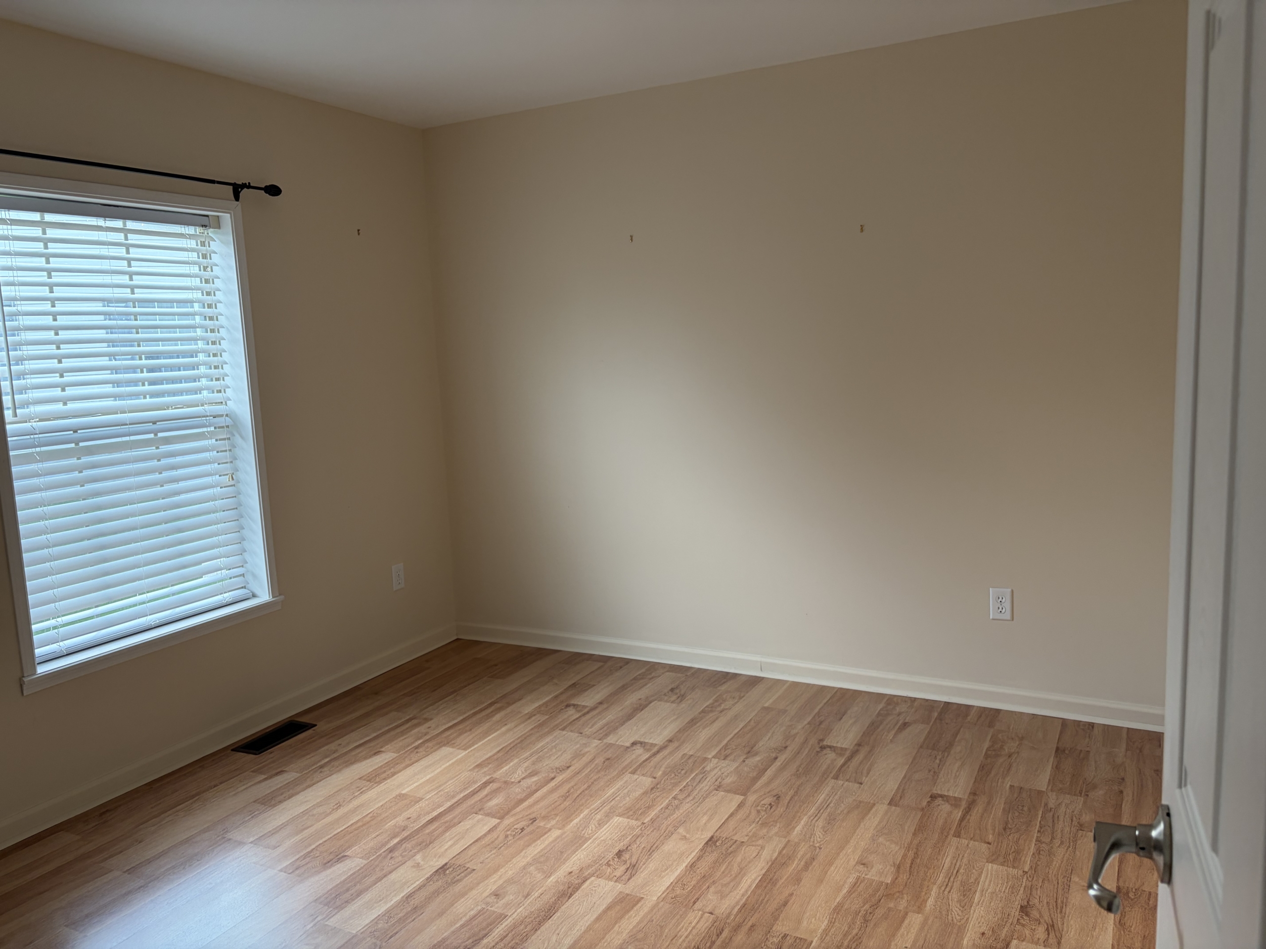 Empty bedroom with light walls and wood floor.