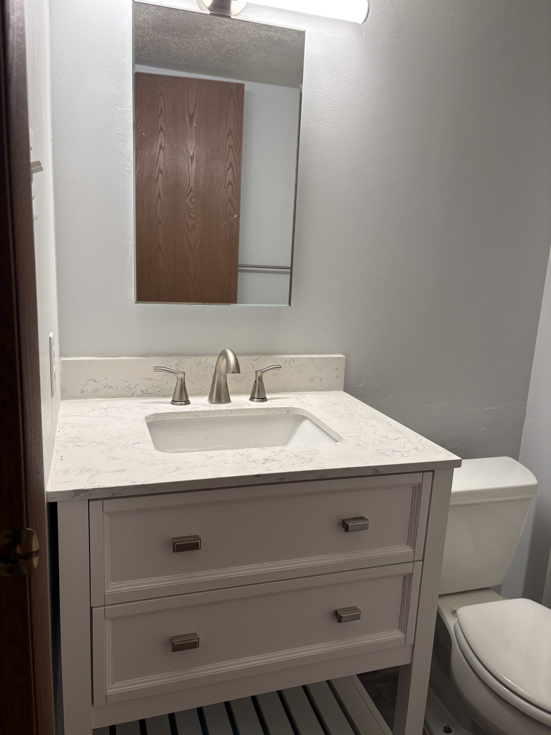 White vanity with marble countertop and toilet